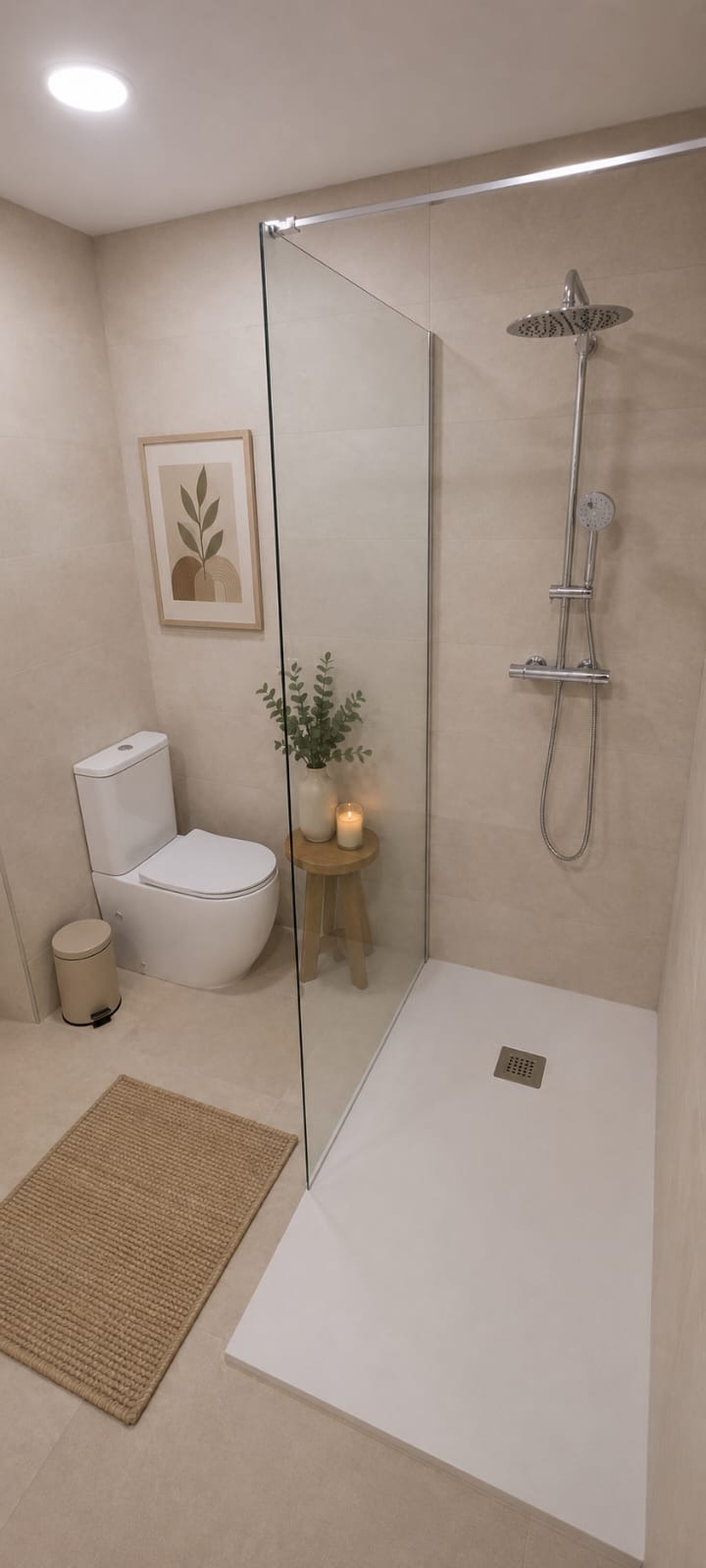 Baño completo con ducha acristalada, inodoro y acabados neutros